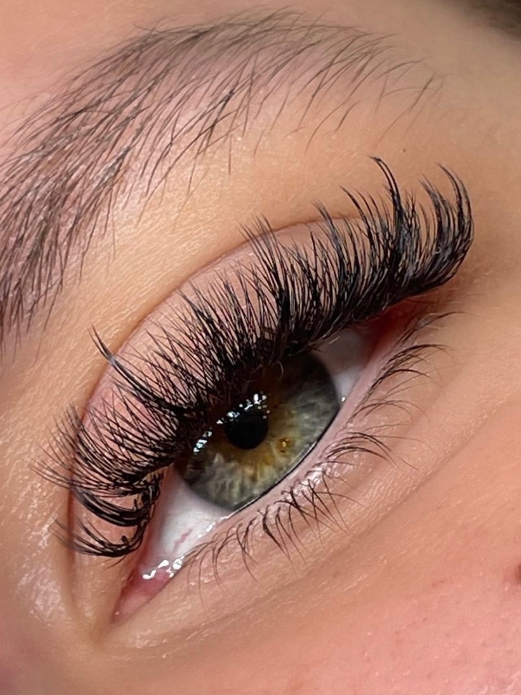 Dichtes Wispy-Lash-Set an einem grünen Auge in der Seitenansicht