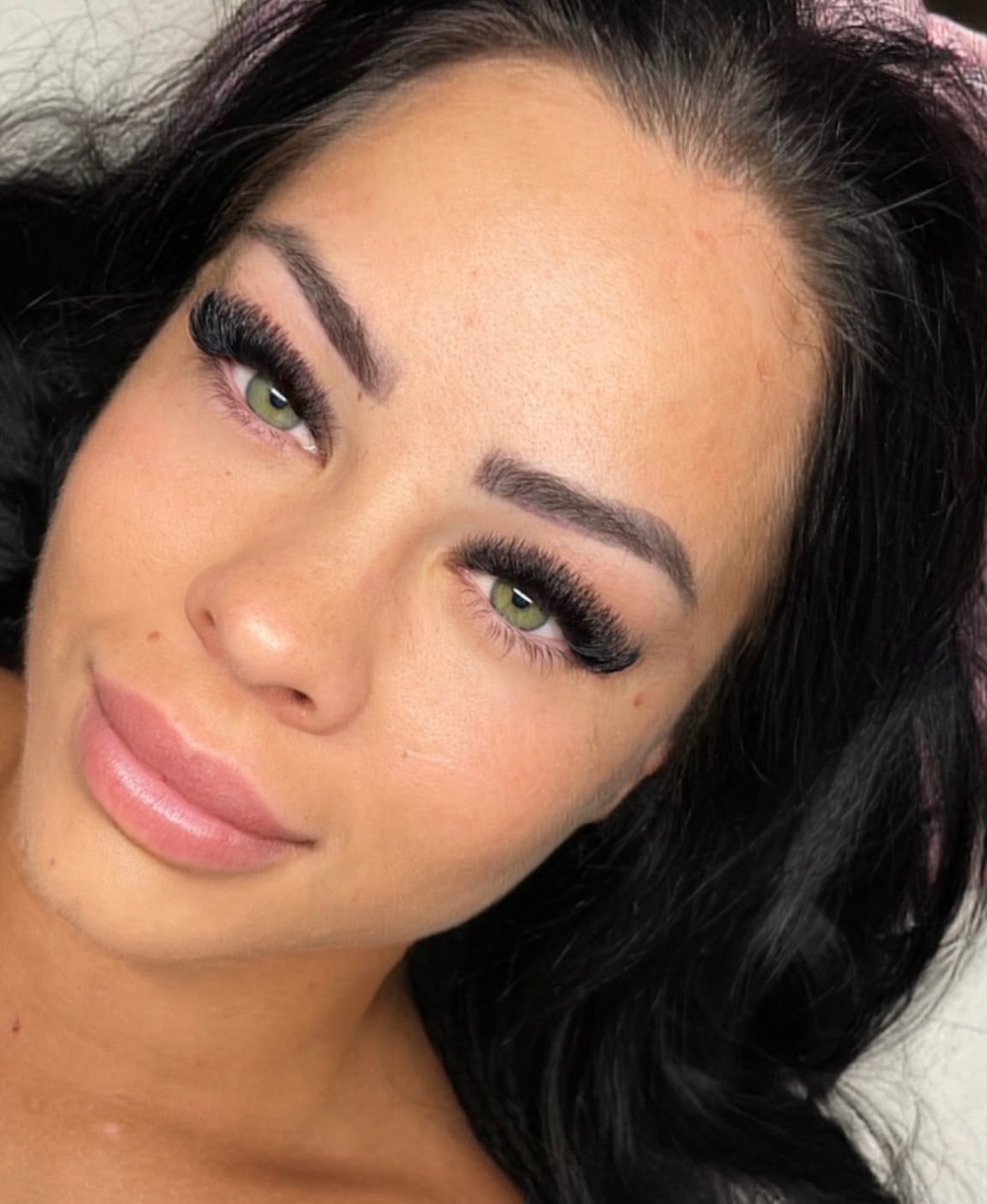 Glamouröser Lash- und Brow-Look im Gesicht mit grünen Augen